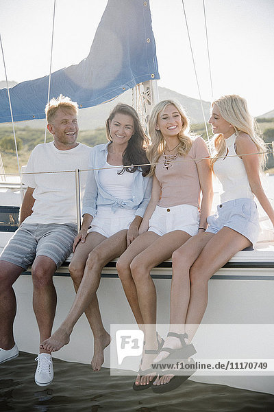 Man  woman and their two blond daughters on a sail boat.