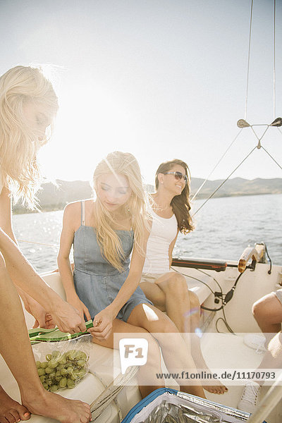 Mutter und ihre beiden blonden Töchter sitzen auf einem Segelboot.