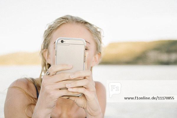 Blond woman taking a picture with a mobile phone.