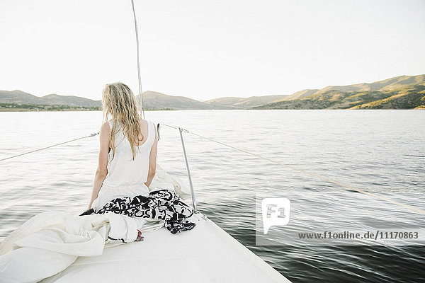 Blond teenage girl sitting on sail boat.