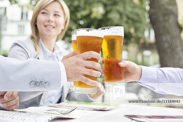 Businesspeople toasting beer glasses at outdoor restaurant