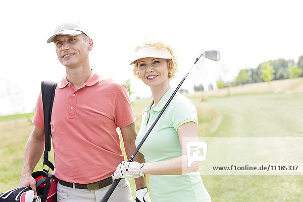 Smiling male and female friends standing at golf course