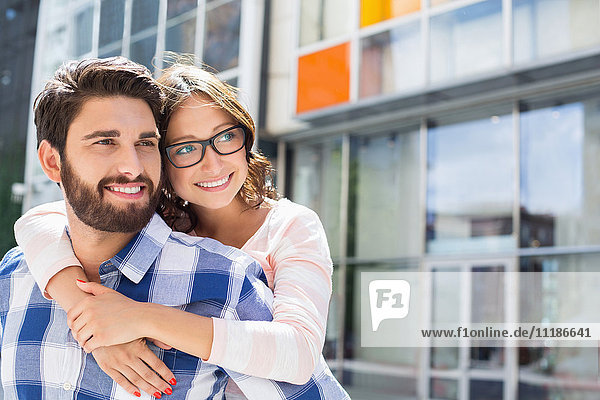Loving man piggybacking woman in city