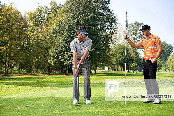 Young man with his friend playing golf in golf course