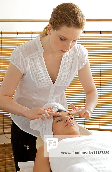 Young woman receiving head massage from masseuse