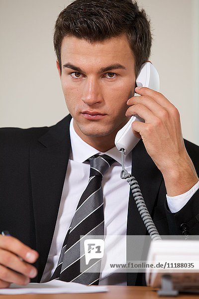 Businessman conversing on landline phone  portrait
