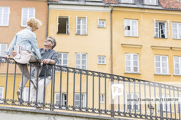Low angle view of loving middle-aged couple by railing against building