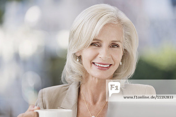 Porträt einer lächelnden älteren Geschäftsfrau beim Kaffeetrinken