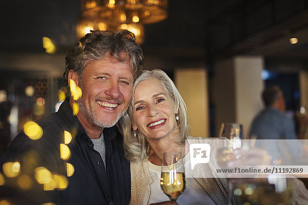 Portrait smiling senior couple toasting white wine glasses in bar
