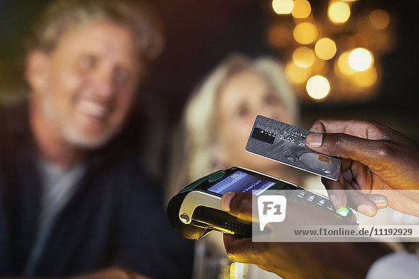 Close up couple paying waiter with credit card reader