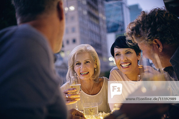 Lächelnde Paare trinken Weißwein und unterhalten sich in einem Straßencafé