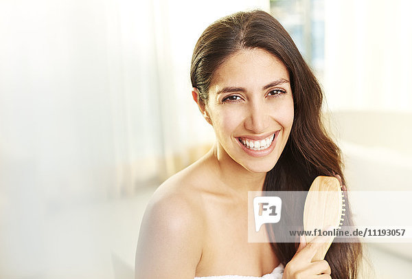 Porträt lächelnde brünette Frau beim Bürsten der Haare