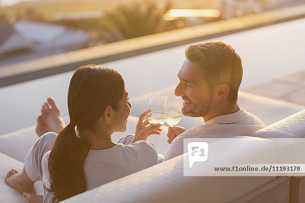 Paar entspannt Toasting Weißwein Gläser auf Chaiselongue auf Luxus-Terrasse