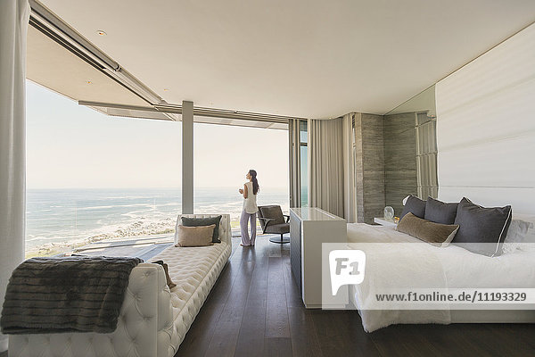 Frau mit Blick auf den Ozean von modernen Luxus Hause Showcase Schlafzimmer