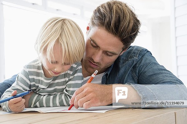 Vater und Sohn machen Hausaufgaben auf dem Tisch