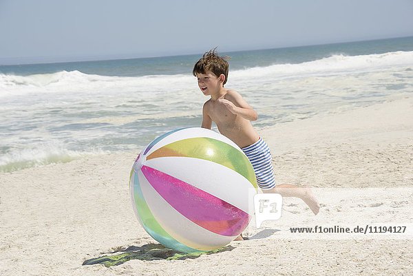 Junge spielt mit einem Strandball am Strand