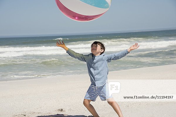 Junge spielt am Strand mit einem Ball