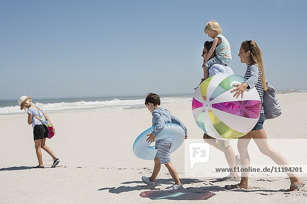 Ein Paar  das mit seinen Kindern am Strand spazieren geht.