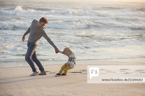 Young man playing with his son on the beach