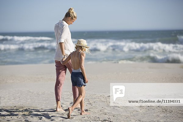 Profil einer Frau mit ihrer Tochter,  die am Strand spazieren geht