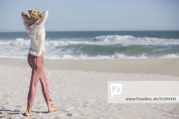 Schöne junge Frau  die am sonnigen Strand spazieren geht