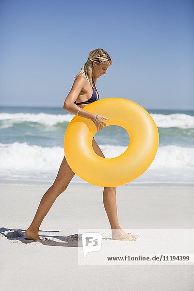 Profil einer Frau mit einem aufblasbaren Ring am Strand