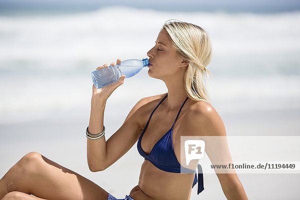 Frau trinkt Wasser am Strand