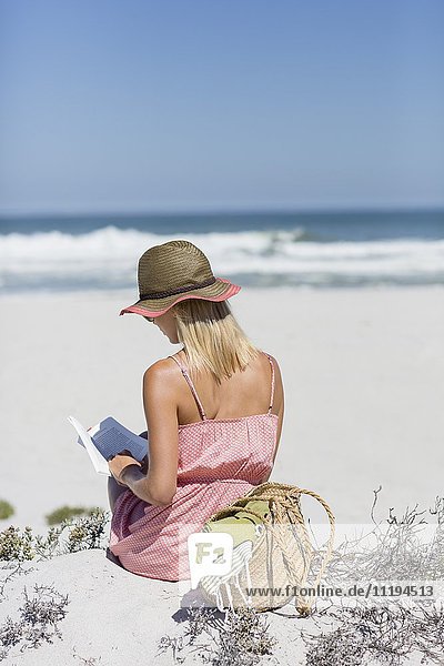 Frau beim Lesen eines Buches am Strand