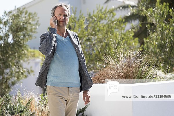 Mann spricht auf einem Handy in einem Garten
