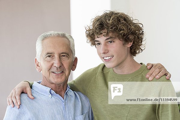 Portrait of happy senior man arm around with his teenage grandson