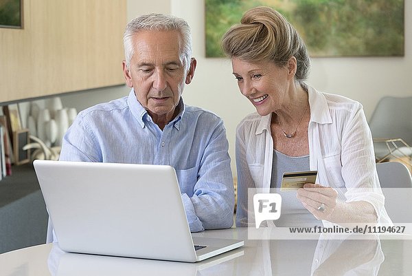 Senior couple shopping online with laptop at home