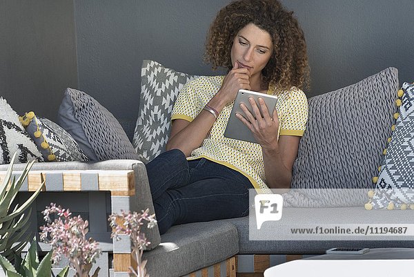 Woman sitting on a couch using a digital tablet