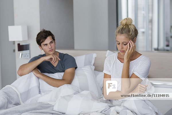 Junges Paar auf dem Bett sitzend mit Beziehungsschwierigkeiten