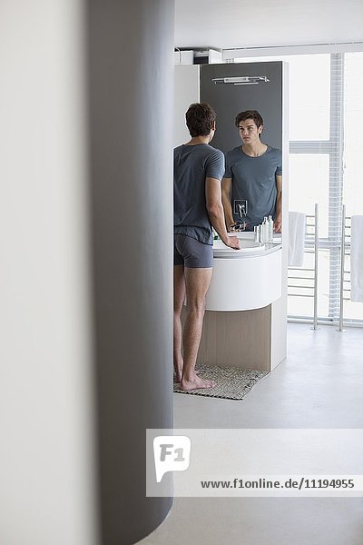 Reflexion eines Mannes im Badezimmerspiegel