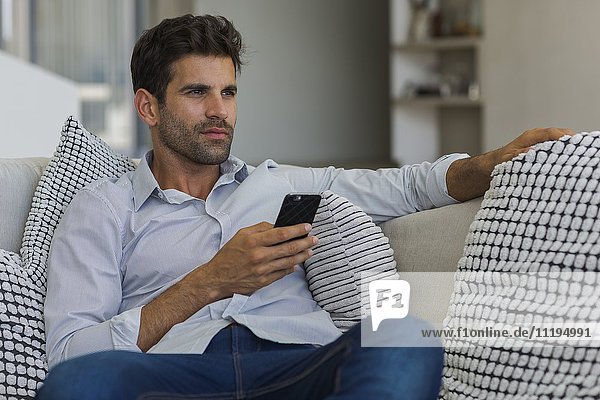 Man sitting on a couch and using a smart phone