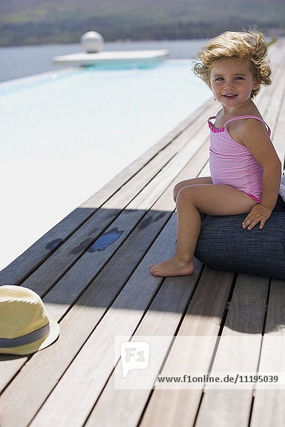 Fröhliches kleines Mädchen sitzt auf einer Promenade