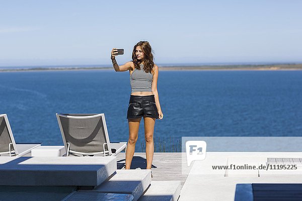 Schöne junge Frau  die Selfie mit einem Smartphone nimmt.