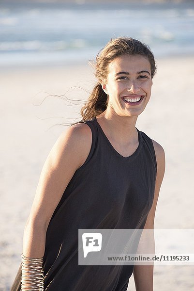 Schöne junge Frau  die am Strand lächelt.