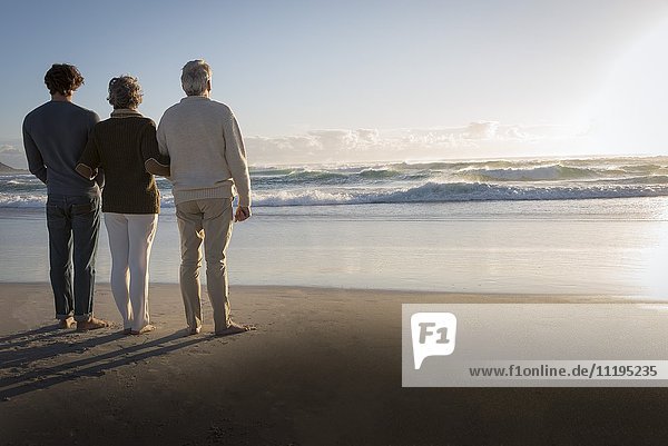 Familie mit Blick auf das Meer am Strand