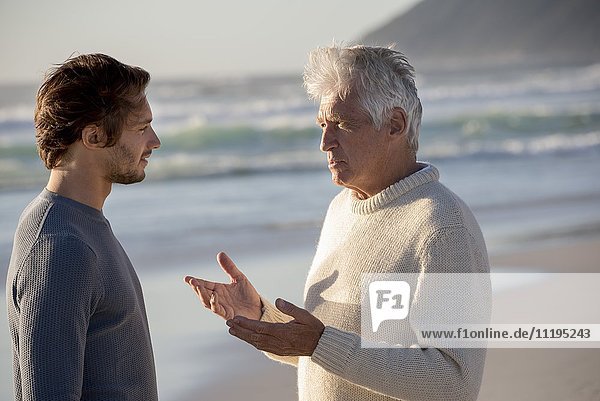 Glücklicher Vater und Sohn im Gespräch am Strand