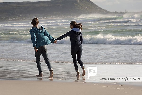 Ein glückliches junges Paar läuft am Strand.