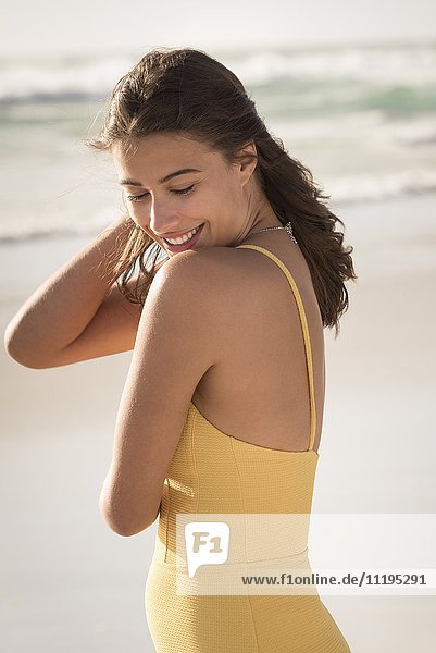 Fröhliche junge Frau am Strand stehend
