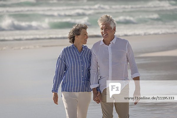 Happy senior couple walking on beach