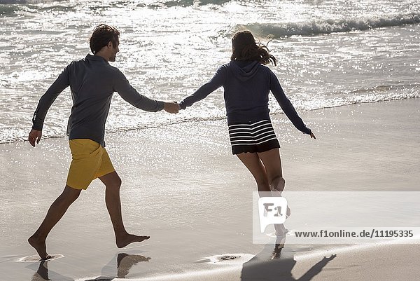 Rückansicht eines jungen Paares am Strand