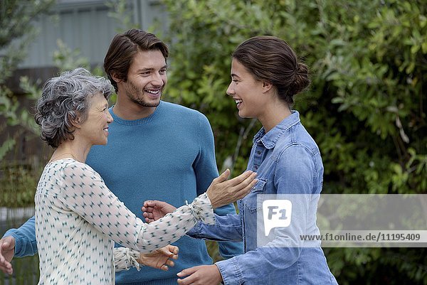 Happy mature woman meet with young couple outside