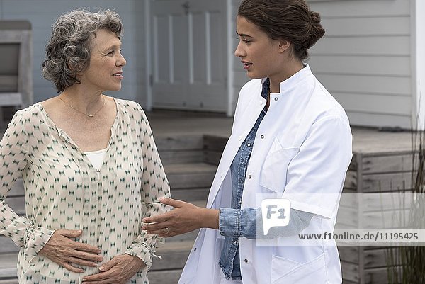 Glückliche Krankenschwester unterstützt ältere Frau im Pflegeheim