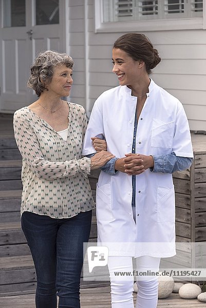 Krankenschwester unterstützt ältere Frau im Pflegeheim