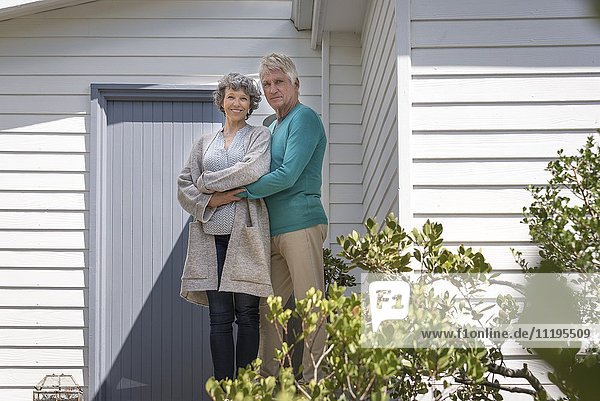 Glückliches Seniorenpaar  das sich außerhalb des Hauses umarmt.