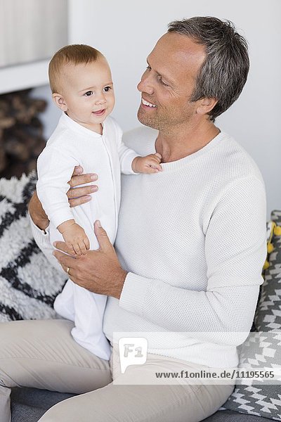 Happy father with his cute baby daughter sitting in living room
