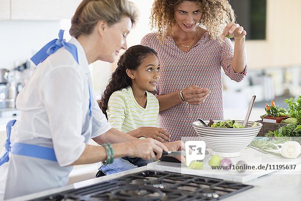 Senior woman with daughter and granddaughter preparing food in kitchen